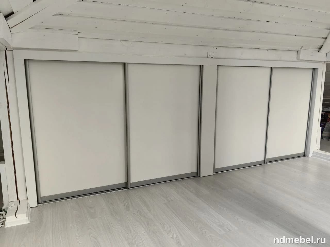 Встроенный шкаф-купе с четырьмя белыми матовыми дверцами и минималистичным серым профилем, оформленный в современном или скандинавском стиле.