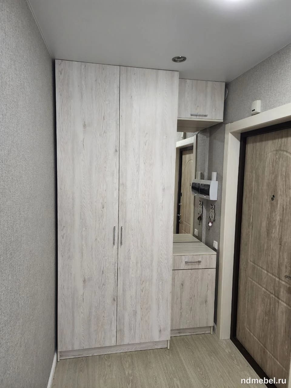 Встроенный или корпусный шкаф-гардероб с прилегающей тумбой и зеркалом, выполненный в современном стиле с отделкой под светлое, выбеленное дерево. Данный комплект мебели идеально подходит для организации хранения в прихожей.