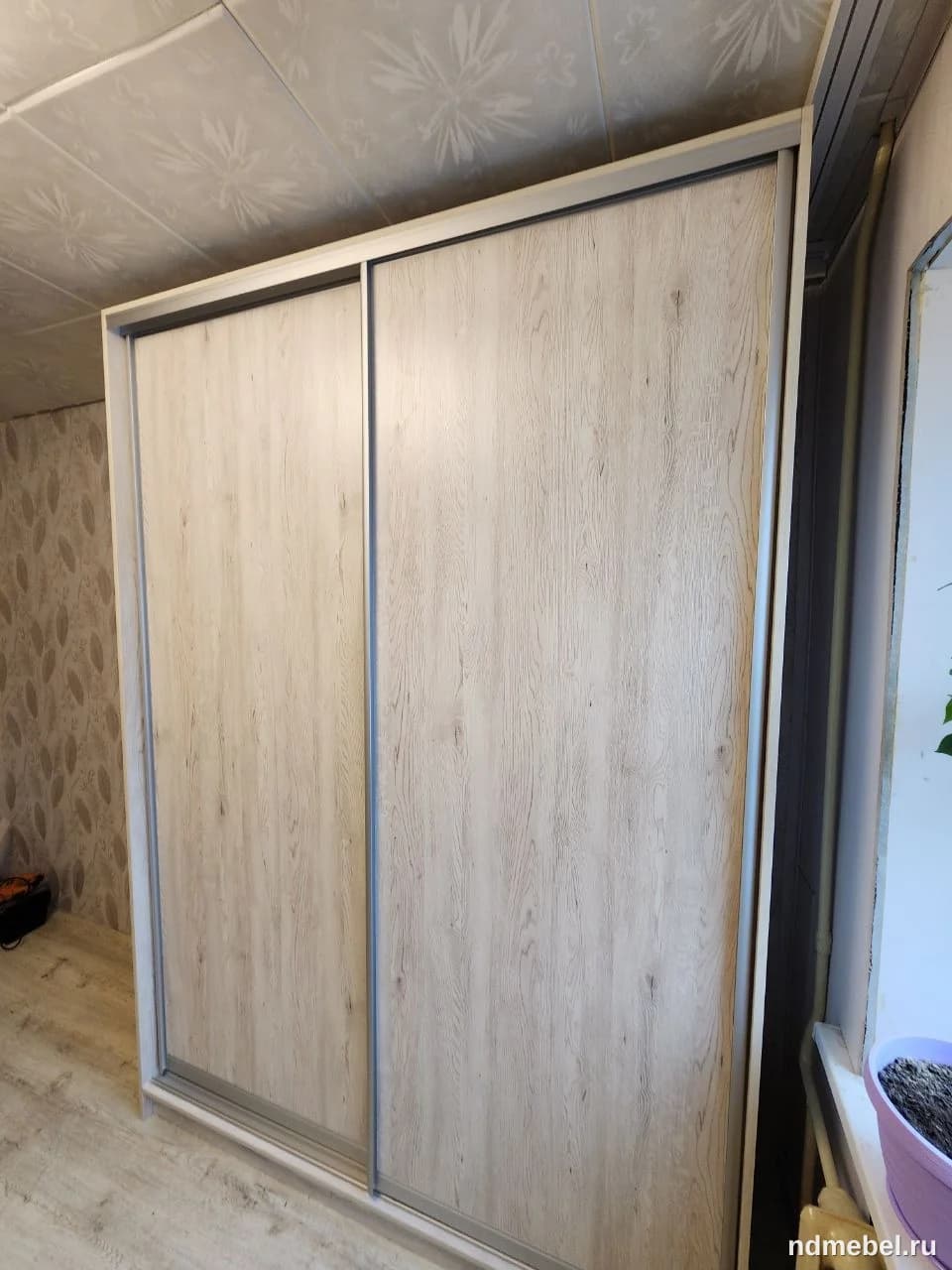 Представлен двухдверный шкаф-купе с фасадами, имитирующими светлое дерево (возможно, выбеленный дуб или ясень). Мебель выполнена в современном минималистичном стиле с использованием алюминиевого профиля для раздвижных дверей.