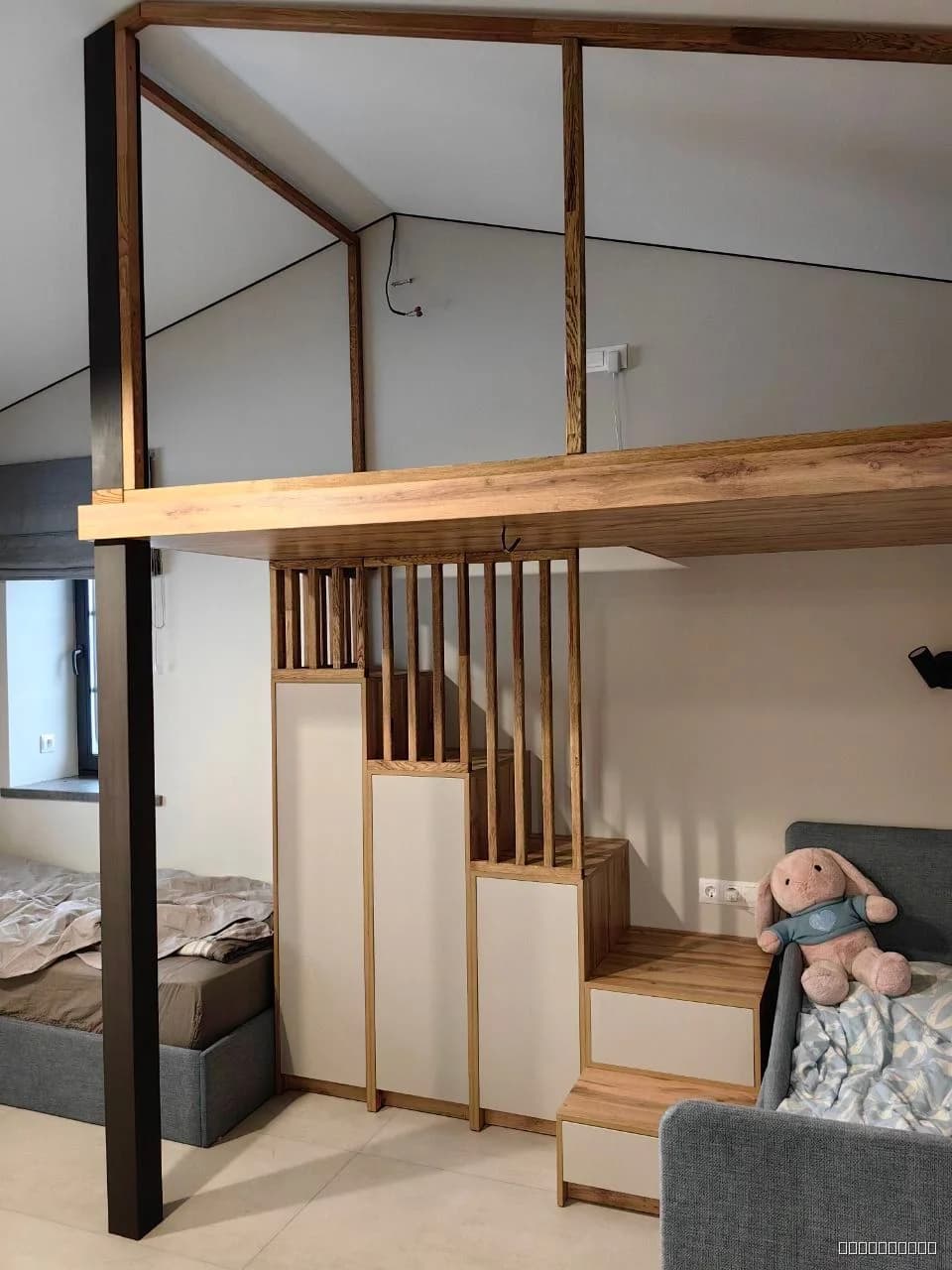 Современная многоуровневая детская кровать с деревянным каркасом, ступенями-хранилищем и светлыми панелями, выполненная в минималистичном стиле.